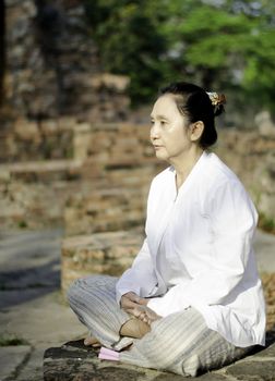 Buddhist woman meditating in ancient temple