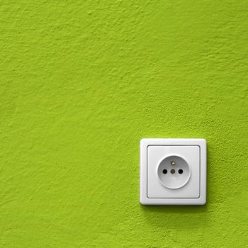 simple white electric socket on green wall