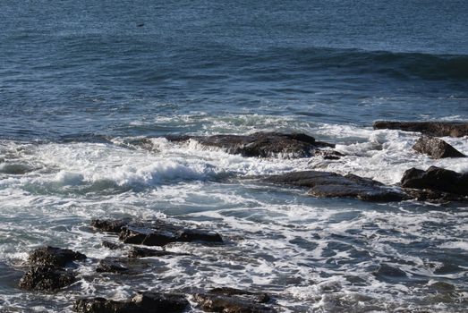 Rolling waves splash over rocks near the shore