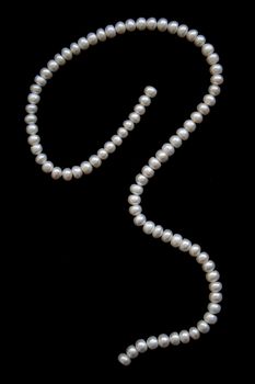 White pearls on the black silk as background 