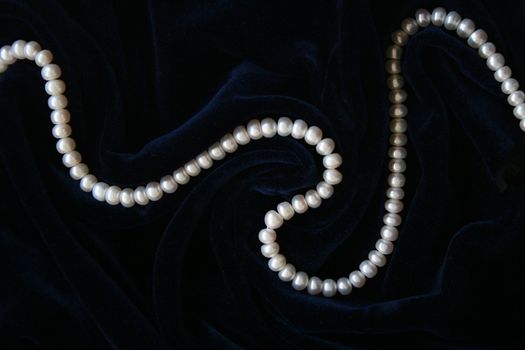White pearls on the black silk as background 