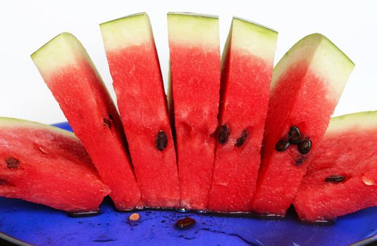 Slices of juicy watermelon served on blue plate on white background