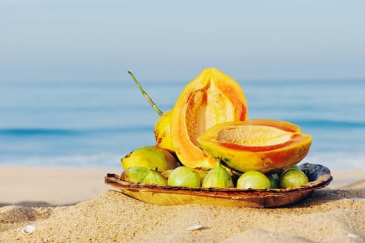 Exotic tropical fruit on the leaves plate, on the sandy beach