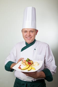 Chef standing and holding a fruit dessert plate