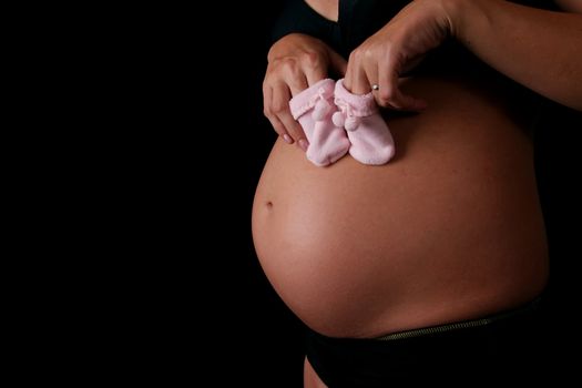 Pregnant holding baby shoes