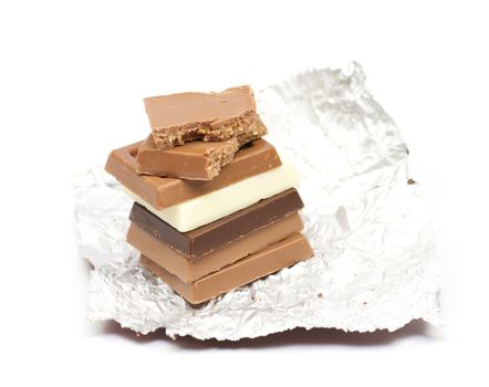 Slices of white, milk and dark chocolate on a foil