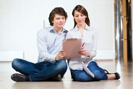 Attractive young man and woman sitting on the floor talking