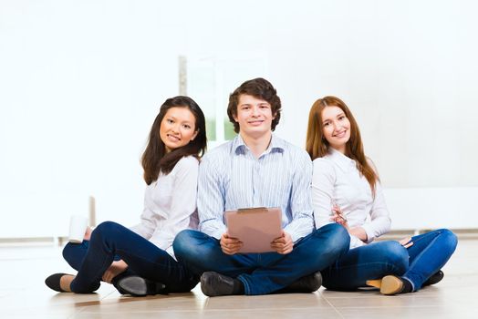 portrait of a group of young people sitting on the floor, man and two attractive women