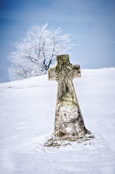 a stone cross surrounded by snow