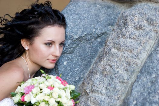 girl with rose bouquet near the stone wall