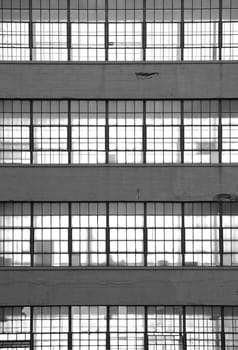 Black and white image of a stack of office windows. Light shines through silhouetting office equipment.