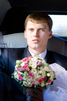 grrom with flower bouquet in the car
