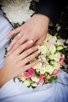 hands with gold rings and flower bouquet