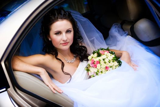 beautiful bride with flowers in the car