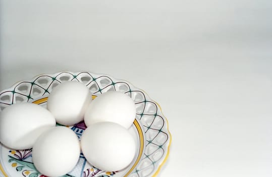 Five white eggs on the ceramic plate