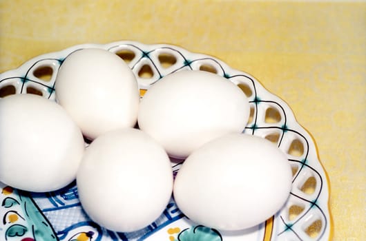 Five eggs on the ceramic plate close up