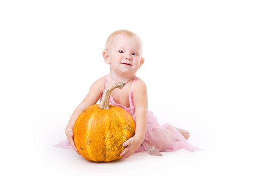 smiling little girl embraces pumpkin and a crystal shoe near by