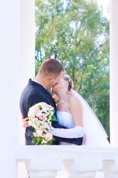 a bride and a groom kiss in the columns