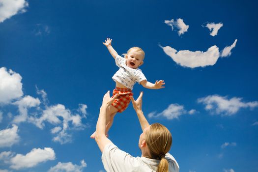 father throw his daughter over blue sky and clouds smile
