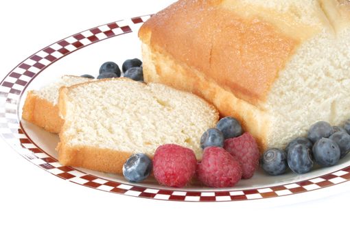 Pound cake slices with fresh fruit on a plate and shot on a white background.  