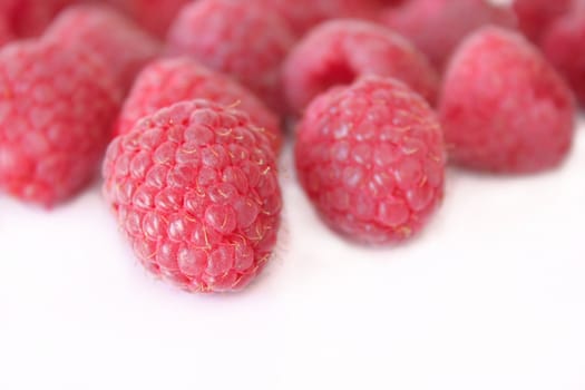 A group of raspberries on a white background.  Copyspace is available.