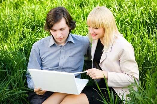 boy and girl dressd for business with laptop on the grass