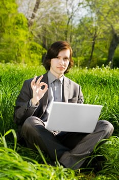 a young business man with a laptop on the grass field