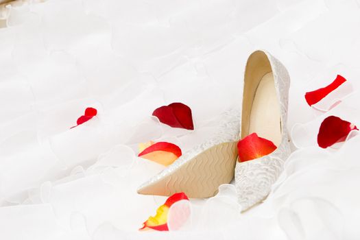 white decorated shoes and red rose and tulip petails on the wedding dress