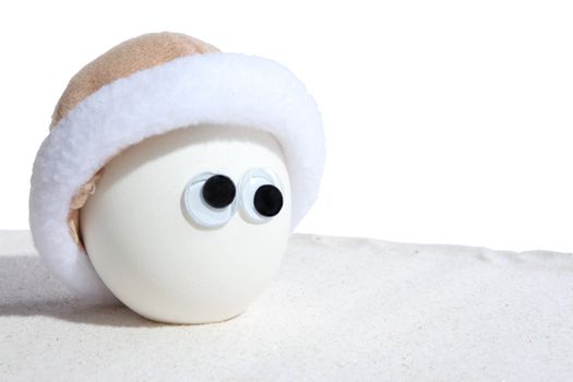 Egg with eyeballs and cap standing on sand. Add own expressions