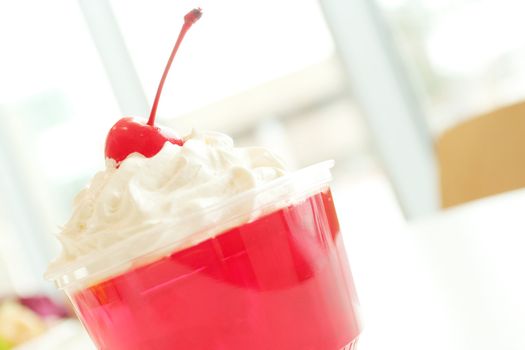 Red delicious gelation dessert with whip cream and cherry