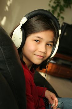 Nine year old girl listening to music with headphones. Part ASian, Scandinavian descent.