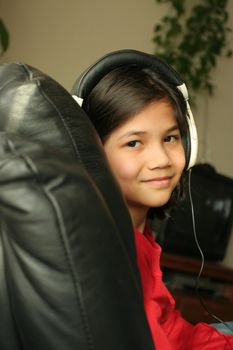 Nine year old girl listening to music with headphones. Part ASian, Scandinavian descent.