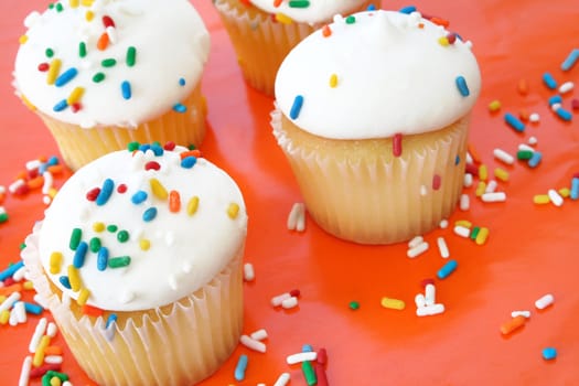 Cupcakes with sprinkles on an orange background.