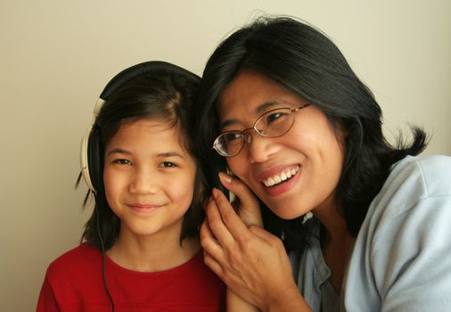 Asian mother and daughter listening to music together.