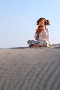 happy little girl play pan pipe in desert