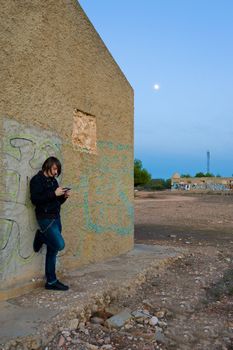 Teen playing with a console in a grunge setting