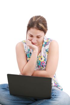 Beautiful young woman sitting on floor with a laptop, isolated on white