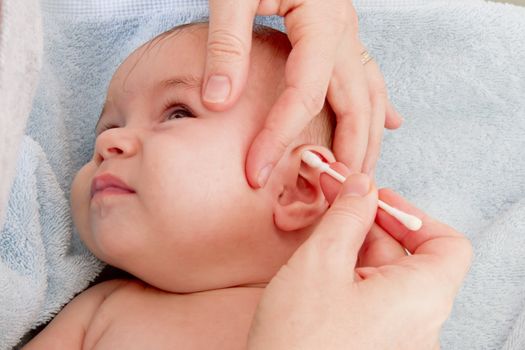 Mother's clean hands are cleaning her baby after the bath.