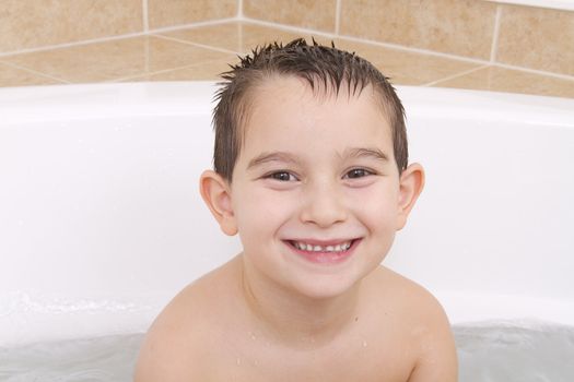 Seven Years old kid is looking at the camera playfully from bathtub.