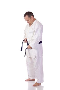 Man in karate-gi fastening his black belt