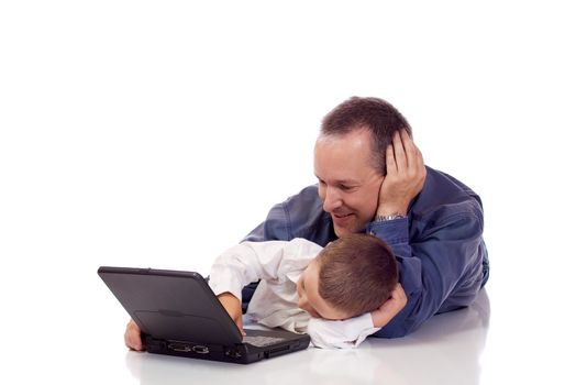 Cute little boy with his father laying on their stomach with a laptop