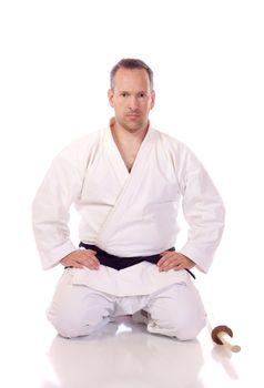 Man in karate-gi holding a boken in the seiza position