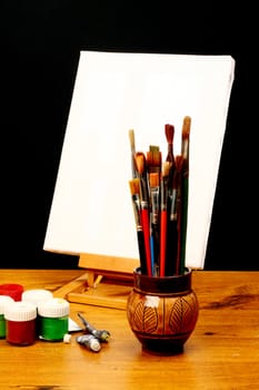 canvas,brushes and easel in black background 