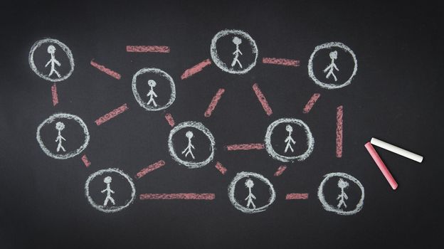 Person drawing a People Network illustration with chalk on a blackboard.