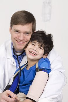 Male doctor in early forties holding five year old disabled patient during office visit