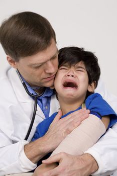 Male doctor in early forties comforting scared five year old disabled patient during office visit