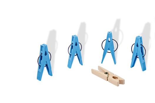 Abstraction of an act of violence.  Closeup of four blue plastic clothespegs located vertically, horizontally near them is a a wooden clothespeg. Long shadows emphasize a situation.