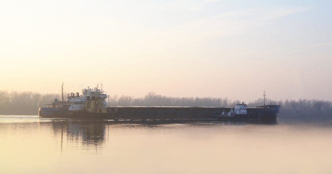 Commercial cargo ship heading for port by tug boat