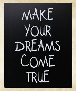 "Make your dreams come true" handwritten with white chalk on a blackboard