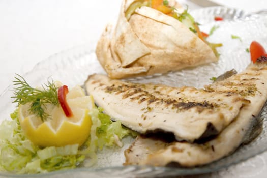 Fried fish with lemon on plate and vegetables